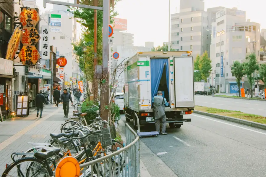 市街地の店舗前で荷降ろしをする配送トラック